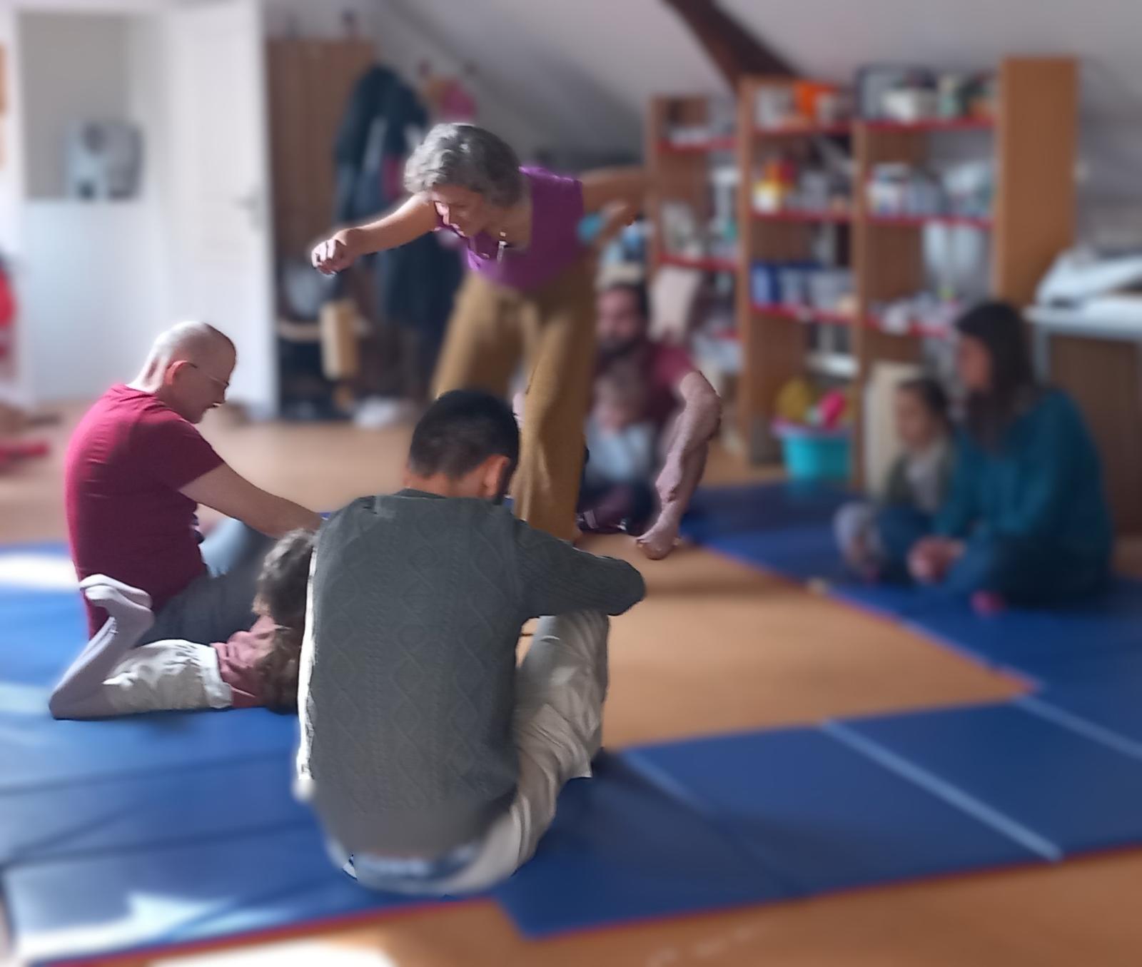Atelier parents-enfants : familles assises sur des tapis bleus dans une salle chaleureuse, partageant un moment créatif guidé par l'art-thérapeute