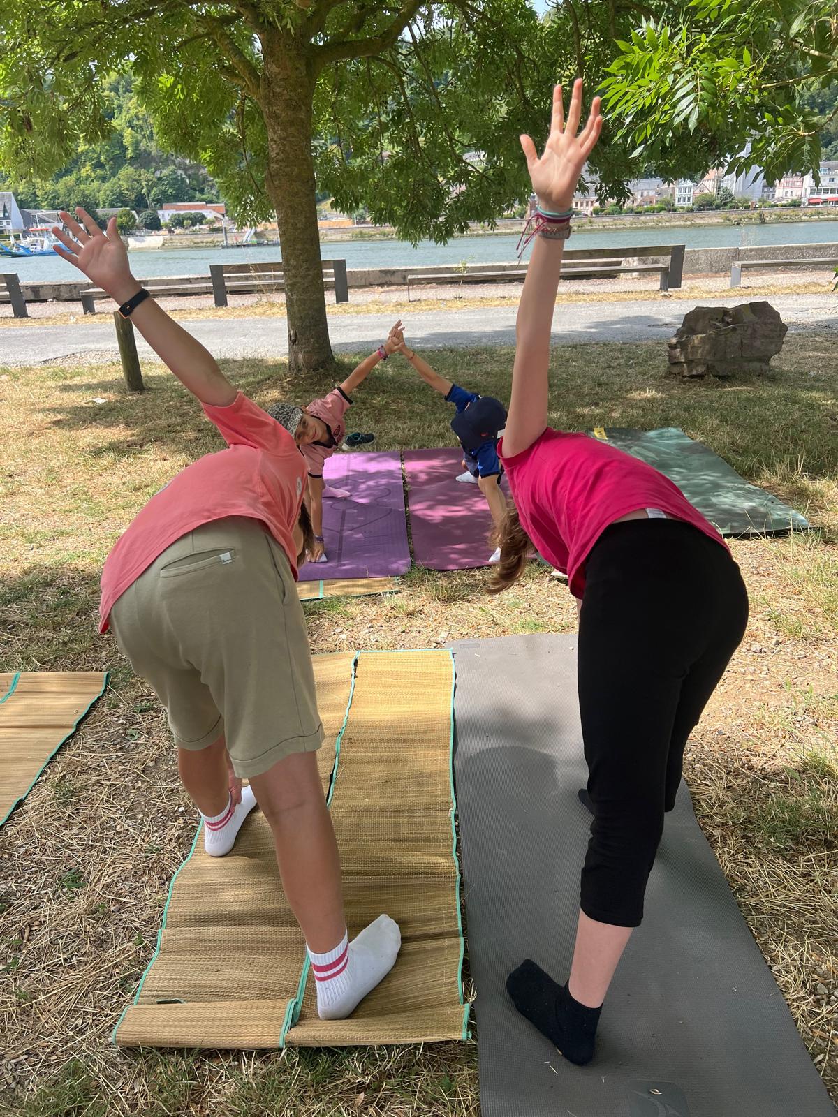 Participantes en plein exercice de mouvement sur des tapis en extérieur, au bord de la Seine à Sahurs, pendant un stage de vacances